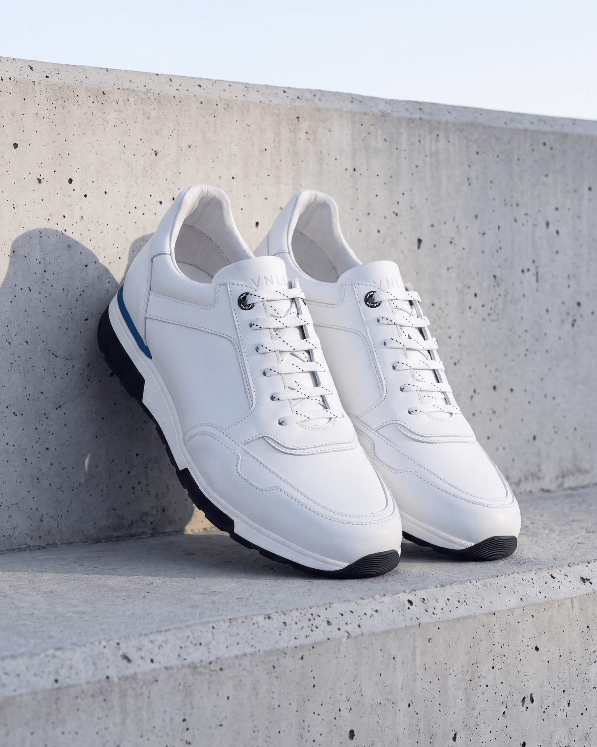 Wit gladleren Positano sneaker – het paar op ruw beton