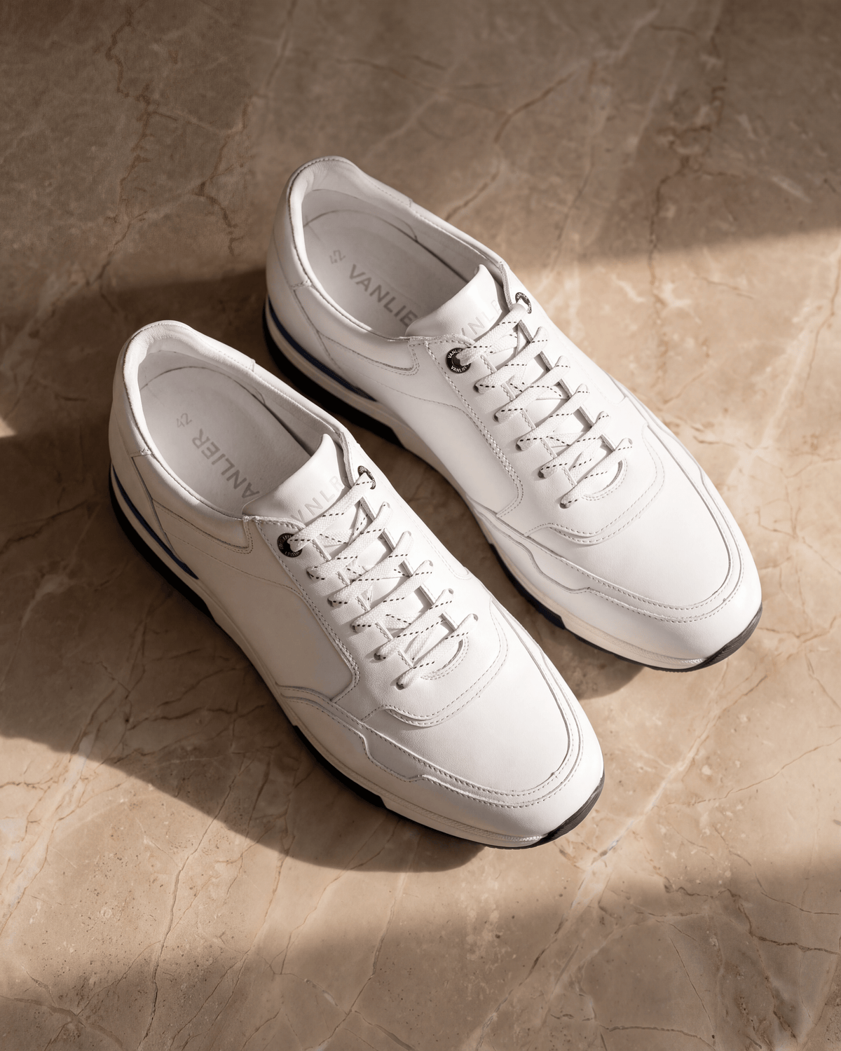 Wit gladleren Positano sneaker – het paar op warm marmer
