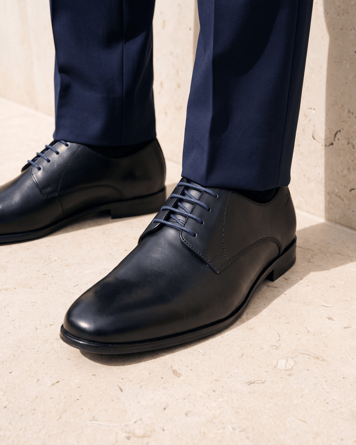 Zwart gladleren Egeus veterschoen – het paar op een kalkstenen vloer
