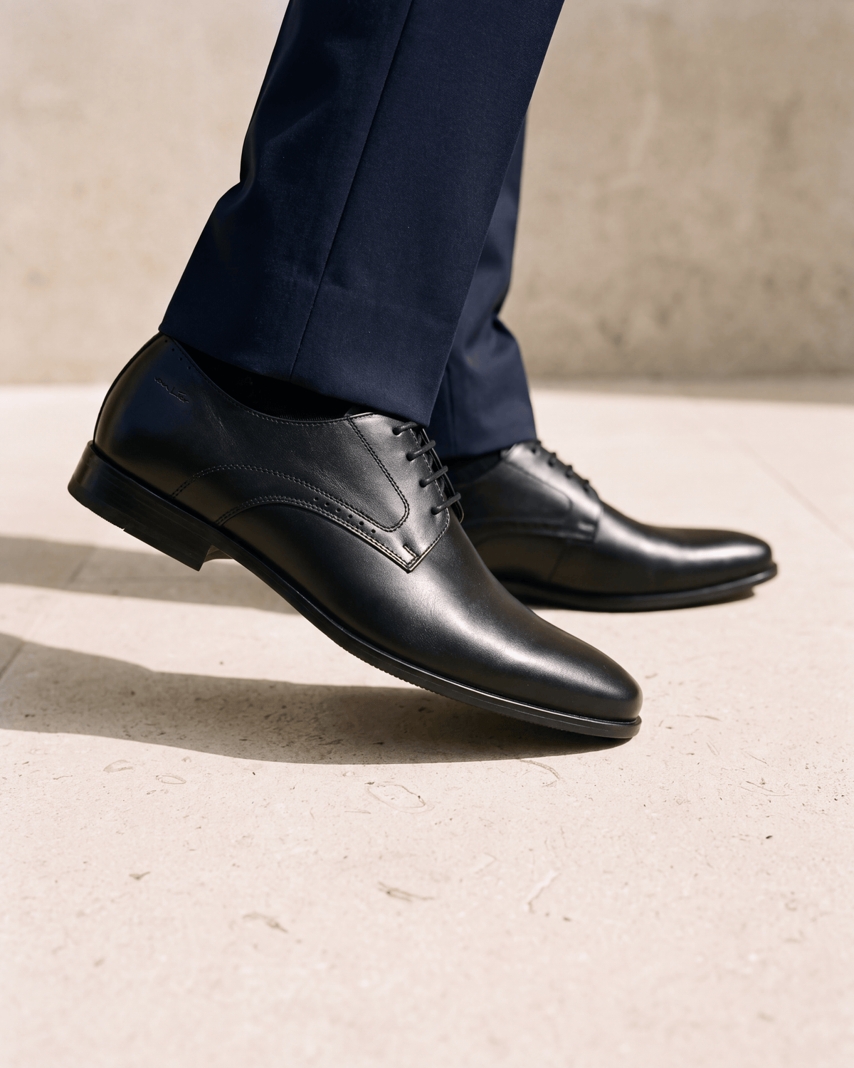 Zwart gladleren met rubberen zool Rhodes veterschoen – close-up van het paar op kalksteen