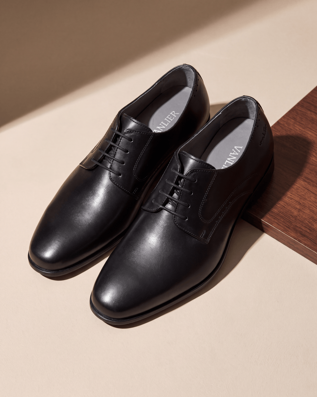Zwart gladleren met rubberen zool Rhodes veterschoen – het paar op hout en pleisterwerk
