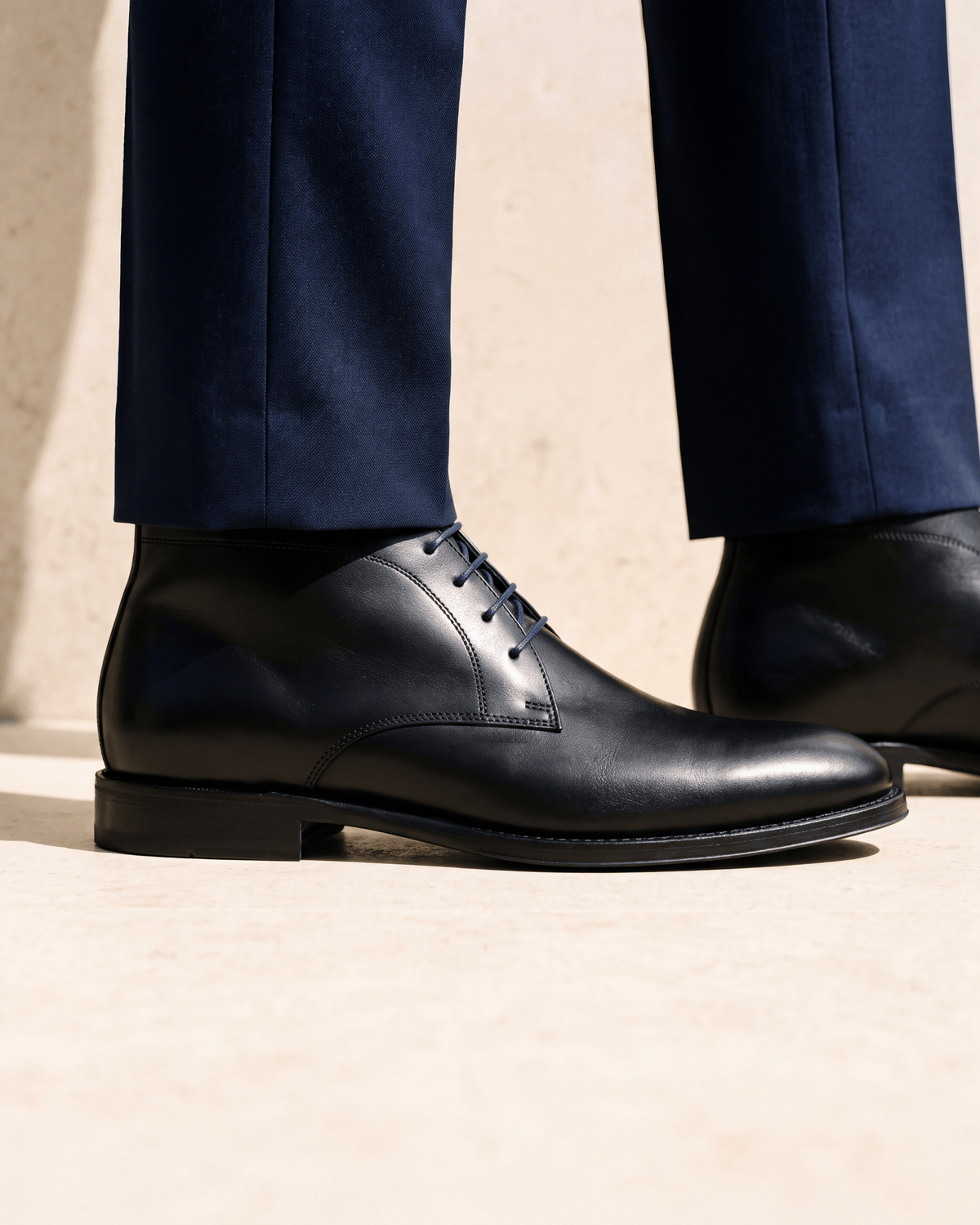 Zwart gladleren met rubberen zool Rhodes halfhoge veterschoen – close-up van het paar op kalksteen