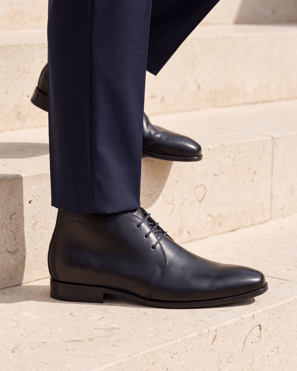 Zwart gladleren met rubberen zool Rhodes halfhoge veterschoen – close-up van het paar op kalksteen