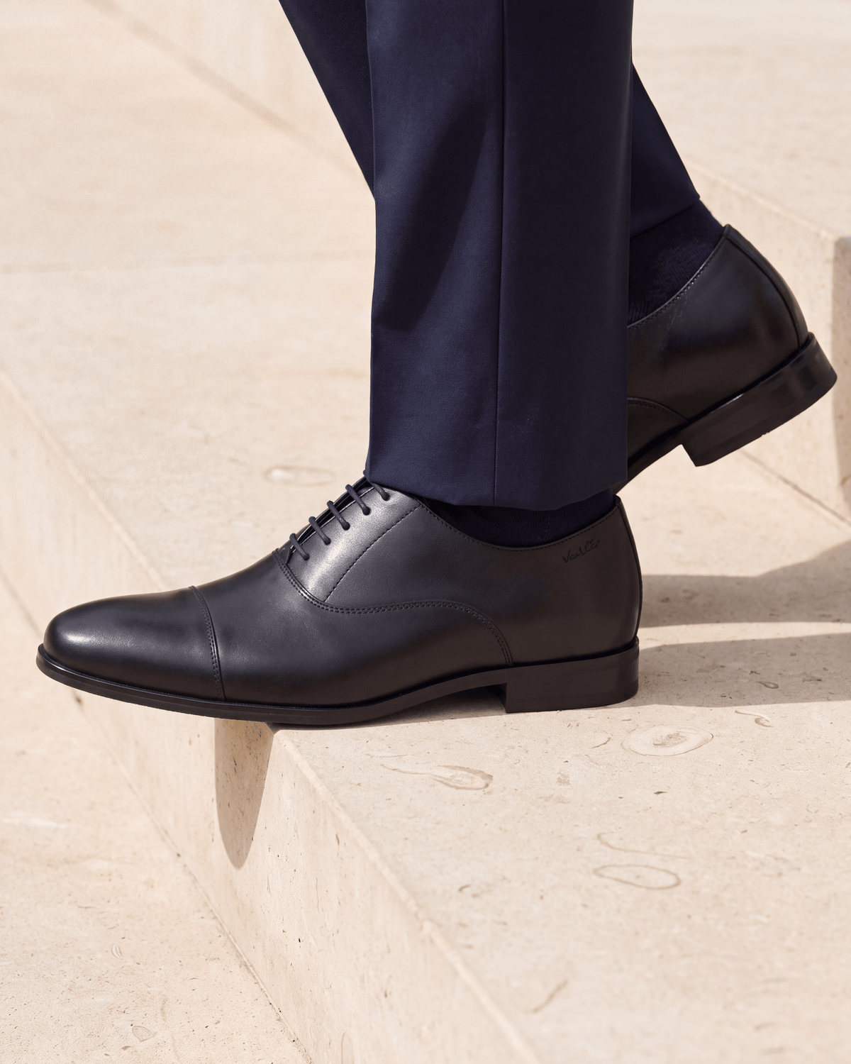 Zwart gladleren met rubberen zool Rhodes veterschoen – het paar op een kalkstenen vloer