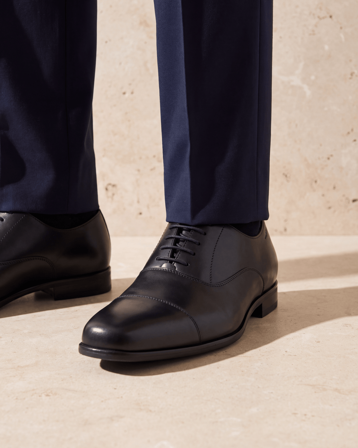 Zwart gladleren met rubberen zool Rhodes veterschoen – close-up van het paar op kalksteen
