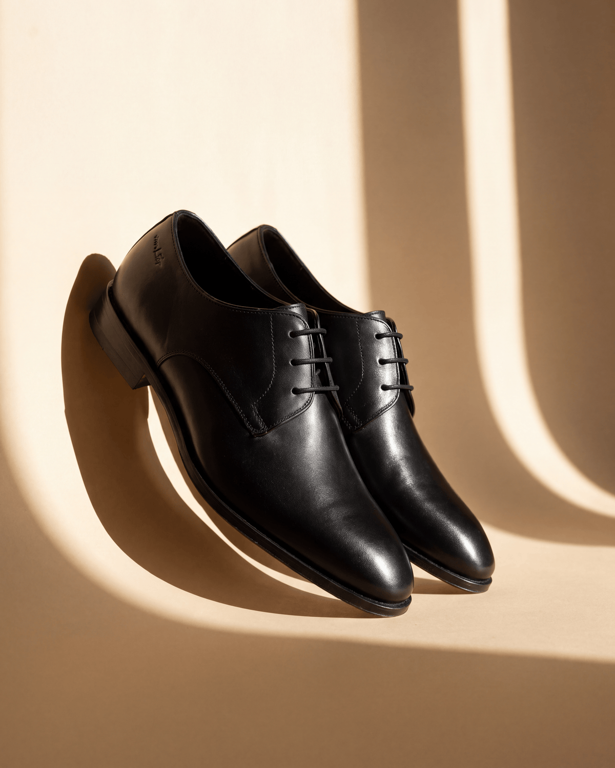 Zwart gladleren Madison veterschoen – detail bij een raam met schaduw