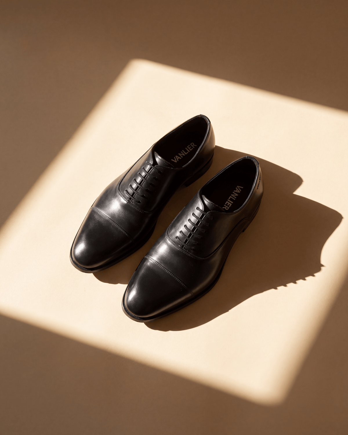 Zwart gladleren Madison veterschoen – detail bij een raam met schaduw
