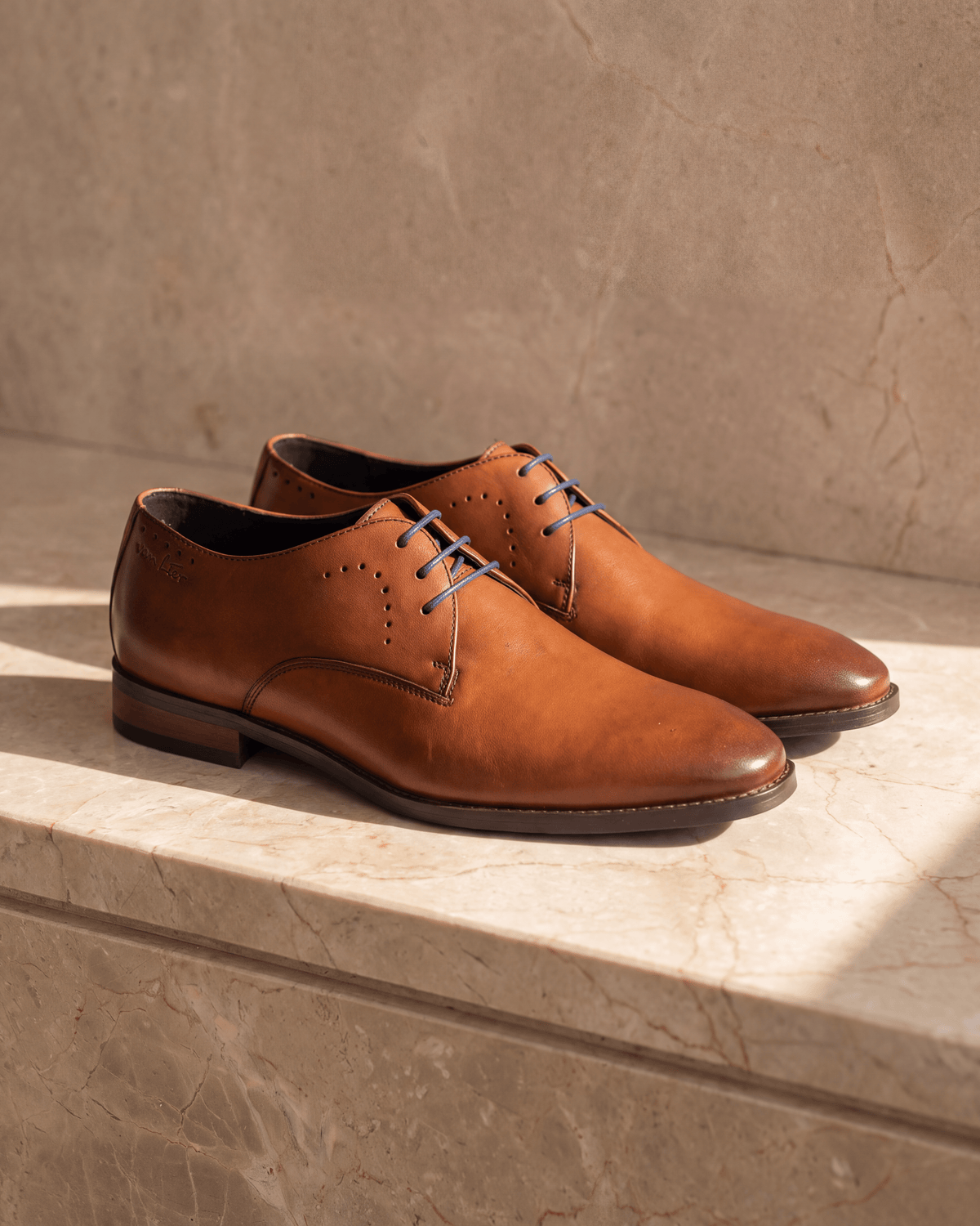 Cognac gladleren Bregenz veterschoen – het paar op warm marmer