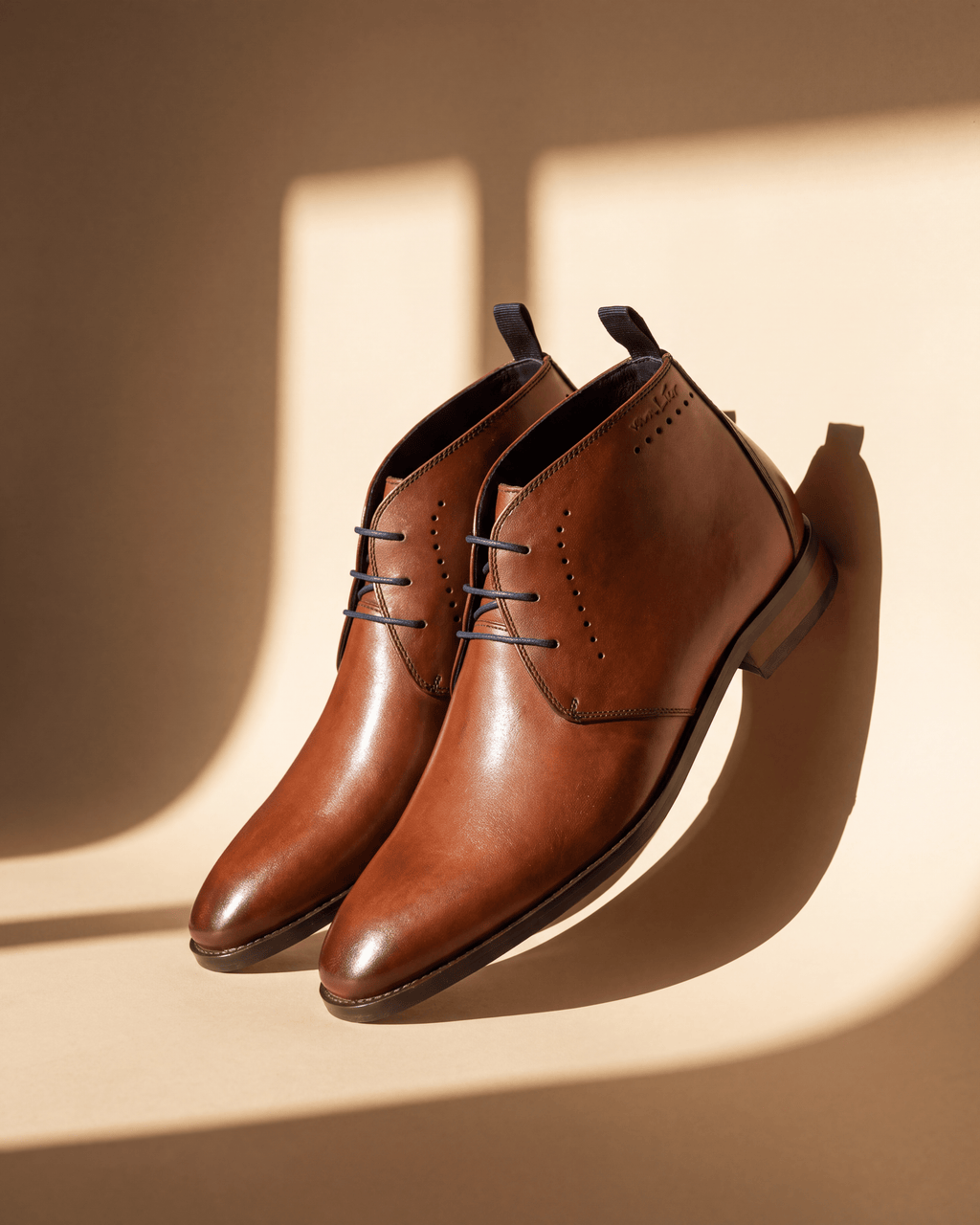 Cognac gladleren Bregenz halfhoge veterschoen – detail bij een raam met schaduw