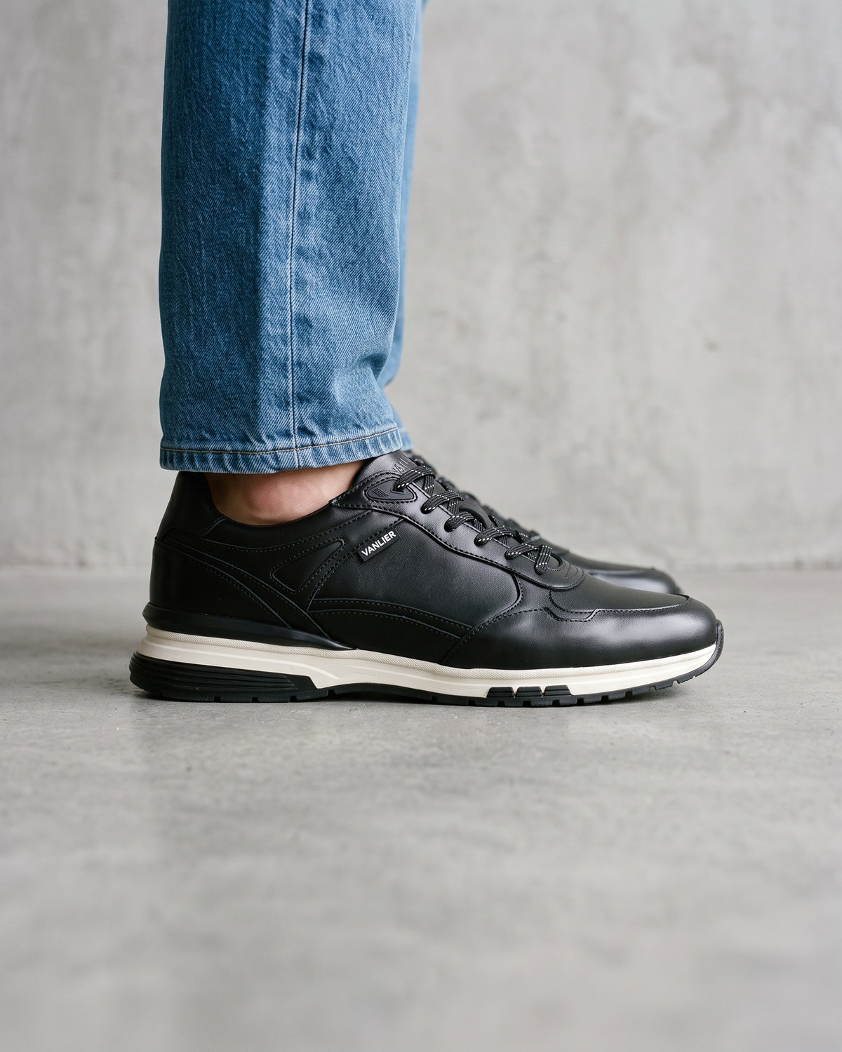 Zwart gladleren Veneto sneaker – close-up van het paar op een betonnen vloer, andere hoek