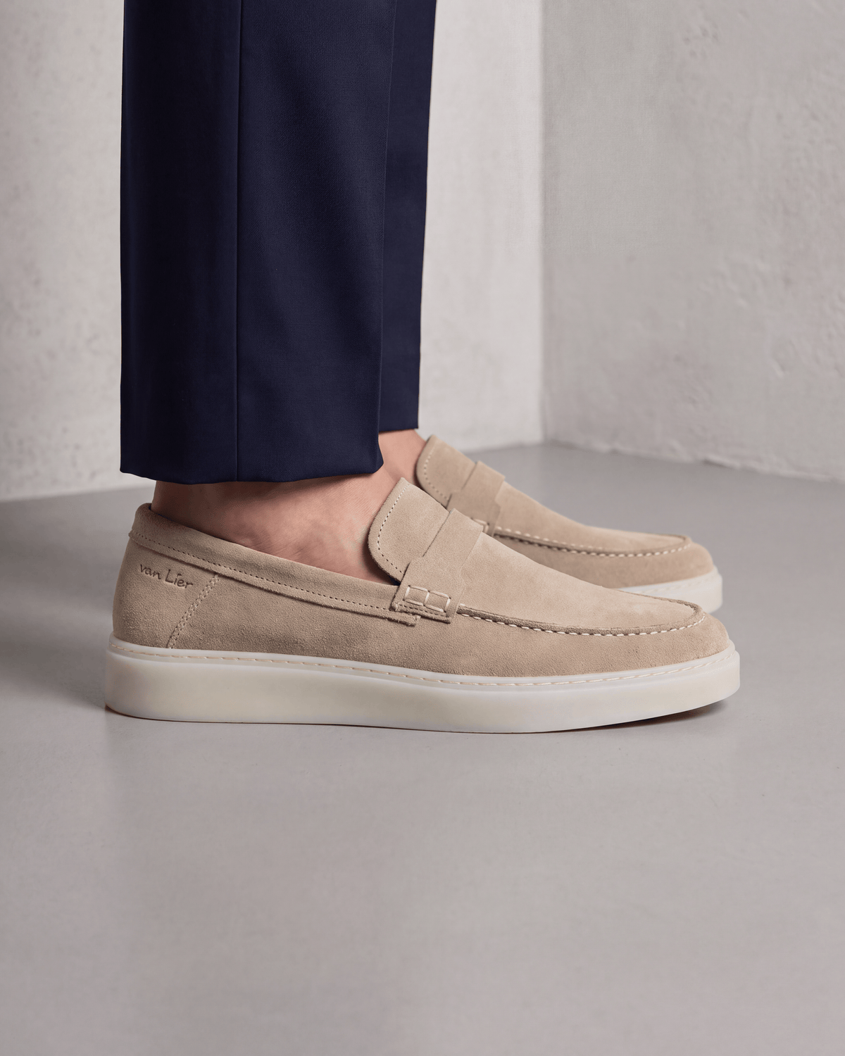 Beige suède Bari loafer – close-up van het paar op beton in een atelier