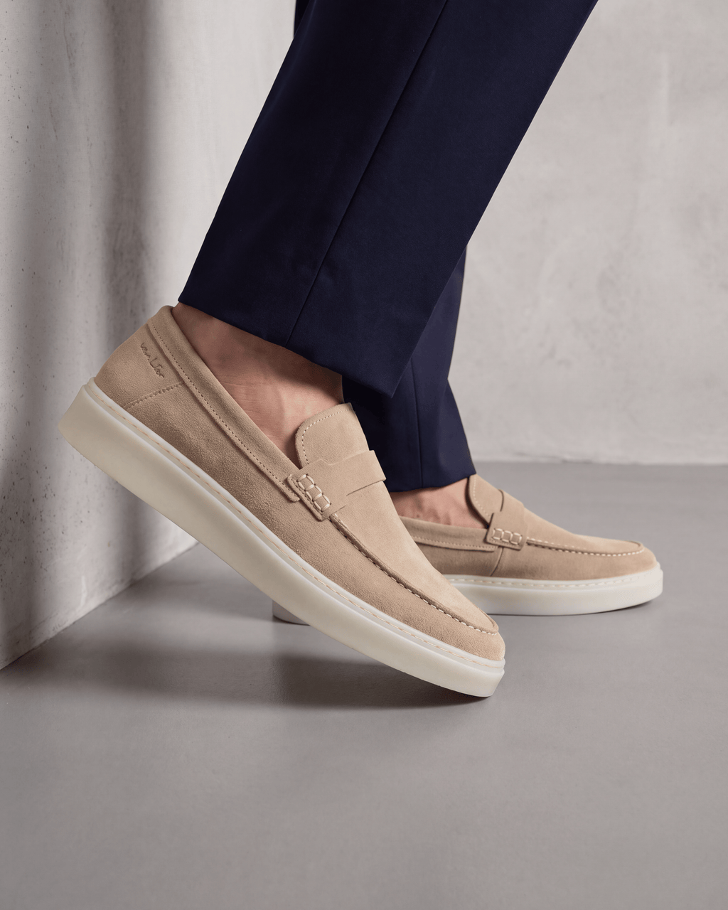Beige suède Bari loafer – close-up van het paar op beton in een atelier