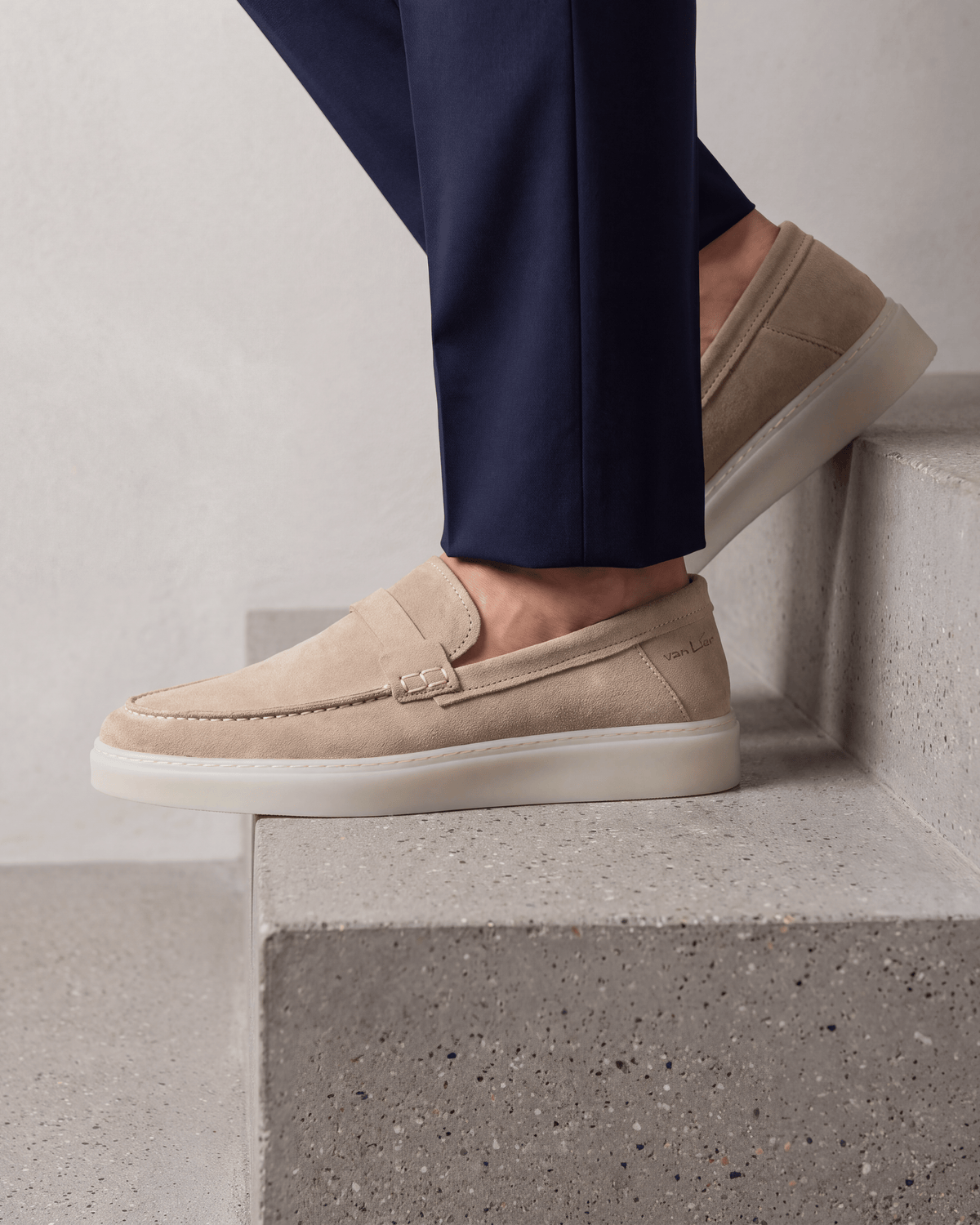 Beige suède Bari loafer – close-up van het paar op beton in een atelier