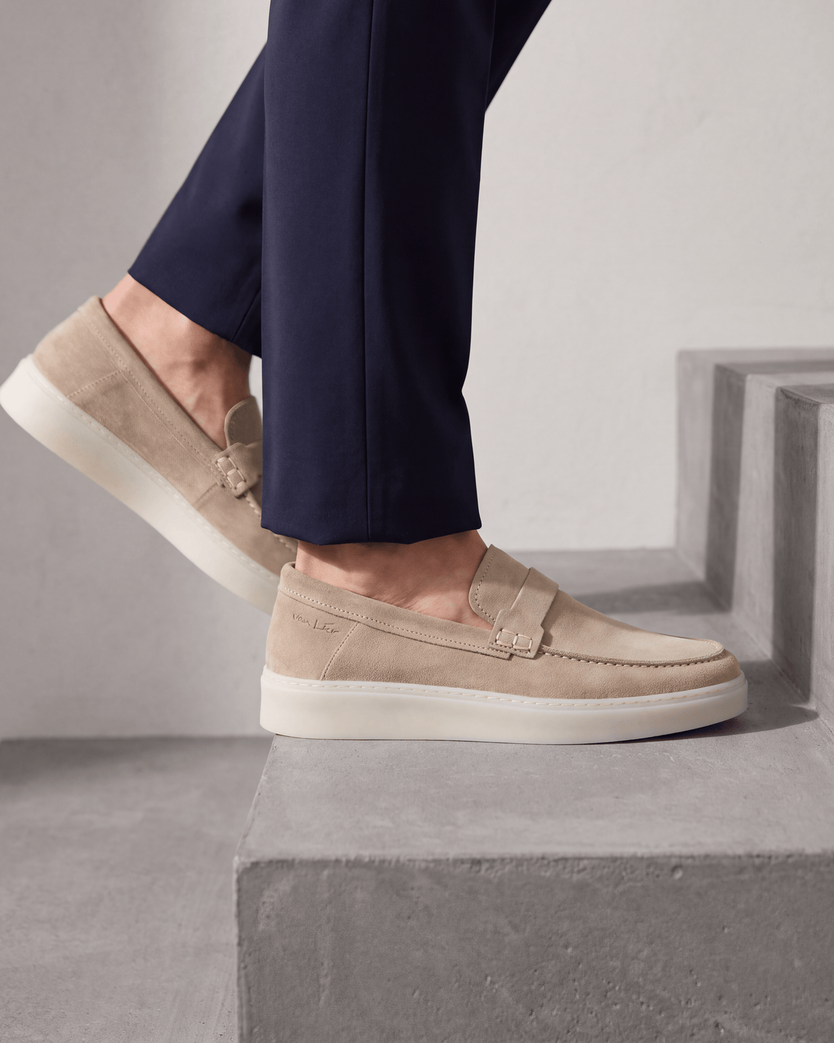 Beige suède Bari loafer – close-up van het paar op beton in een atelier