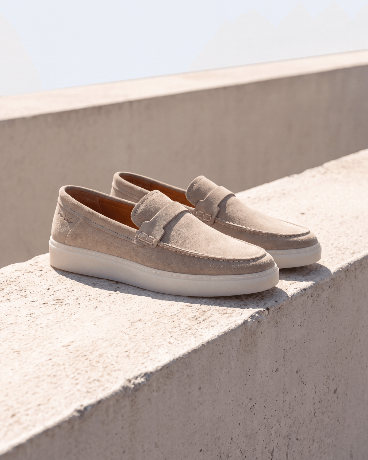 Beige suède Bari loafer – het paar op ruw beton