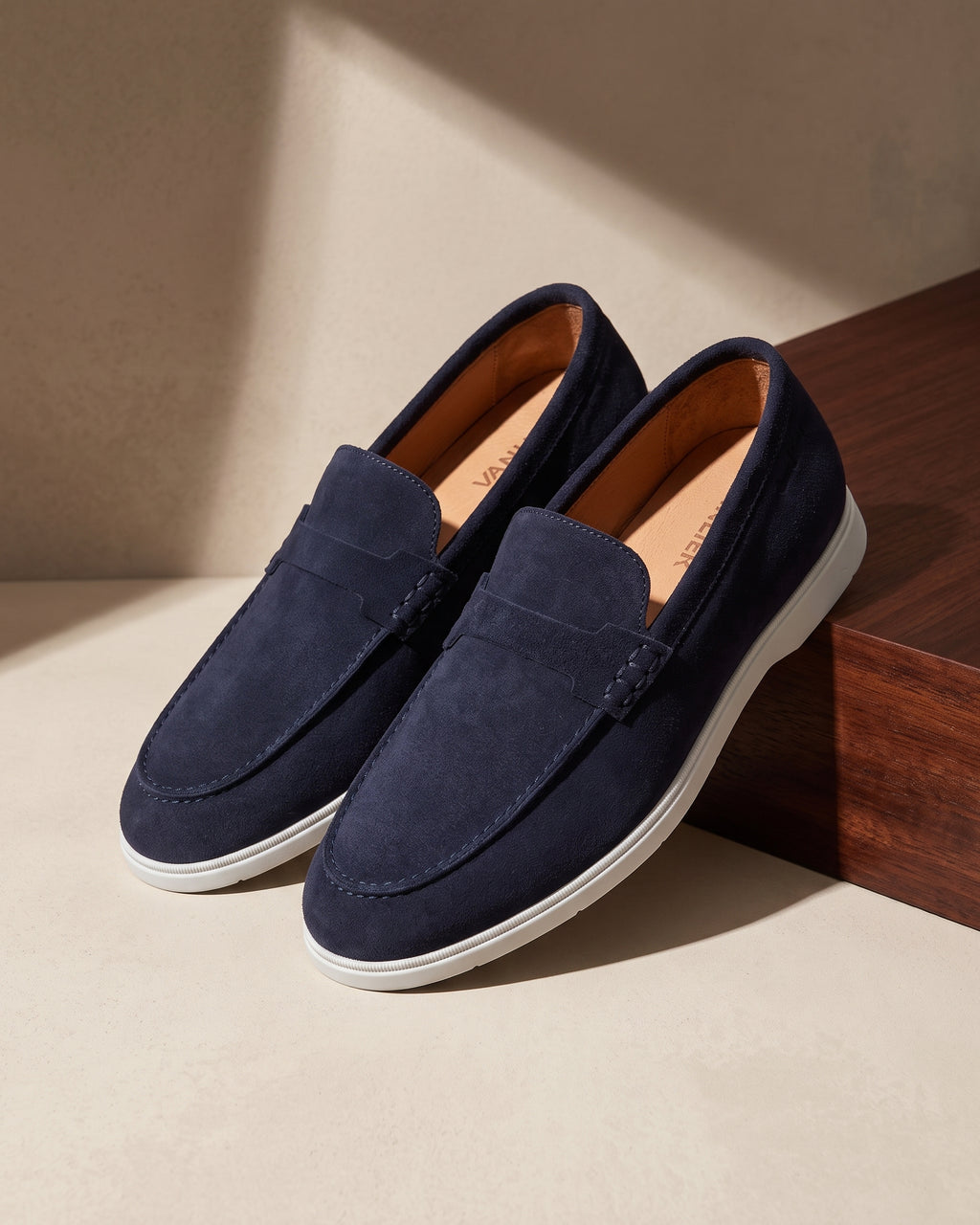 Navy blauw suède Ascona-H loafer – close-up van het paar op hout en pleisterwerk
