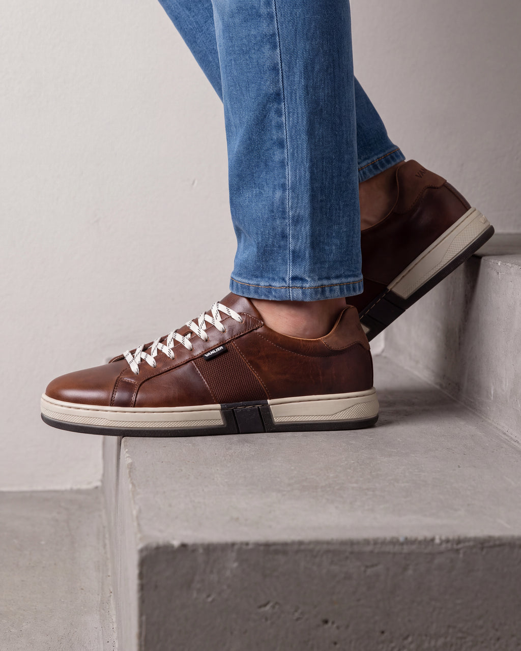 Cognac gladleren Retro sneaker – close-up van het paar in een betonnen atelier, andere hoek
