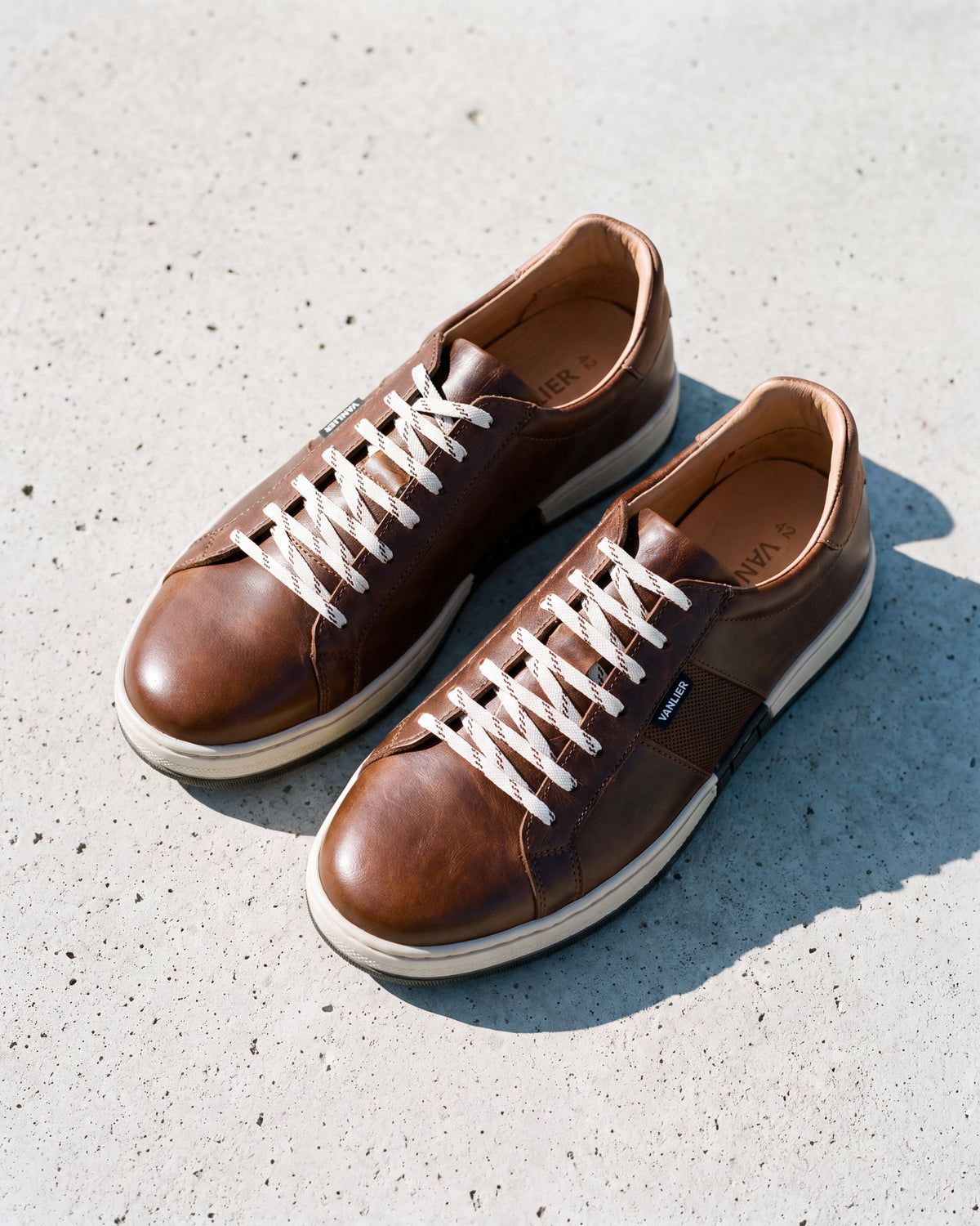 Cognac gladleren Retro sneaker – detail van het paar op ruw beton