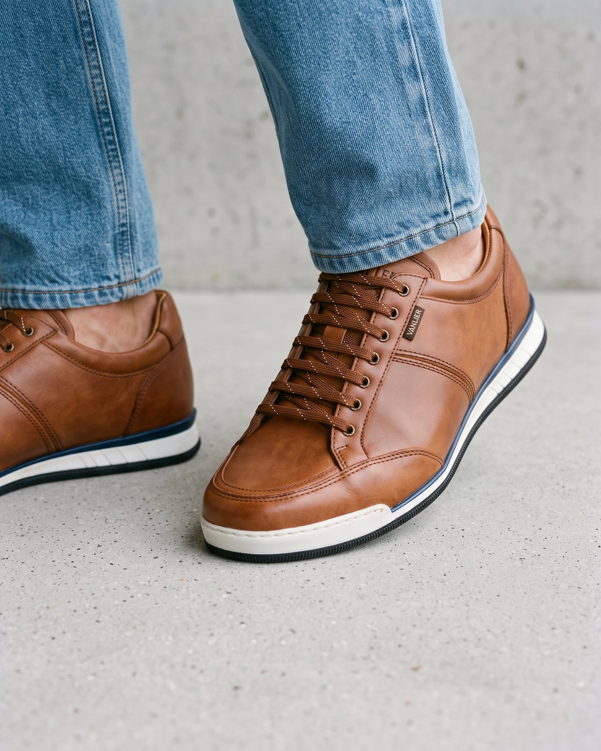 Cognac gladleren Magnus sneaker – close-up van het paar op een ruwe betonnen vloer