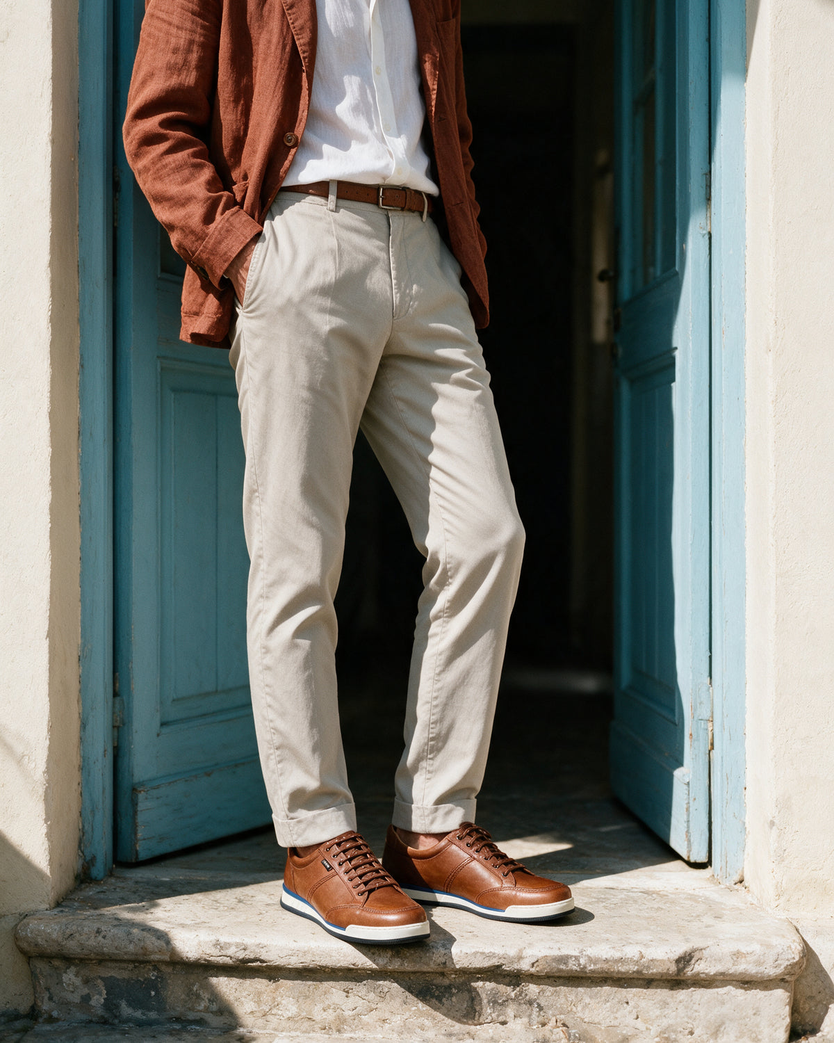 Cognac gladleren Magnus sneaker – gedragen bij een blauwe deur in de zon