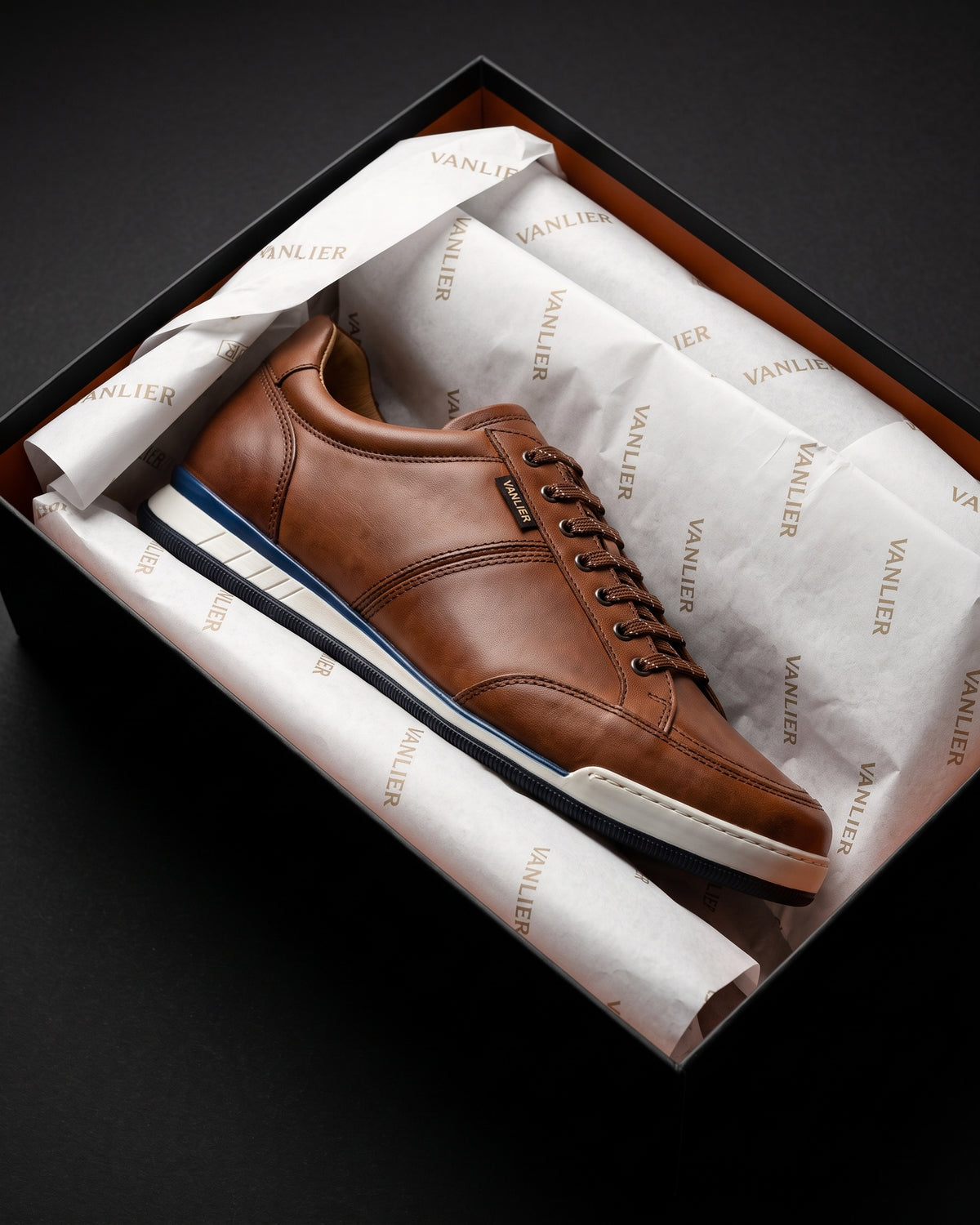 Cognac gladleren Magnus sneaker – in de geopende schoenendoos