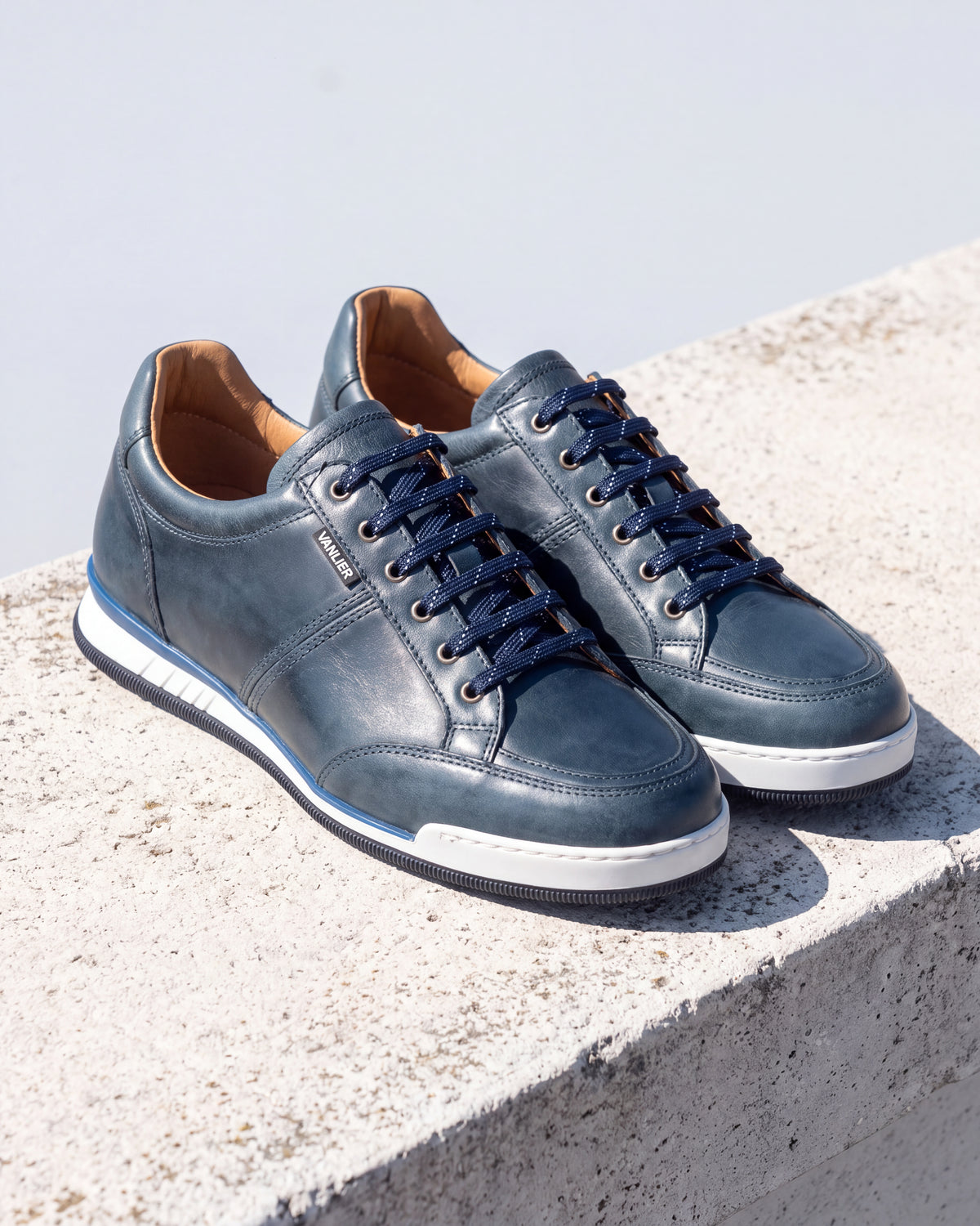 Blauw gladleren Magnus sneaker – detail van het paar op ruw beton