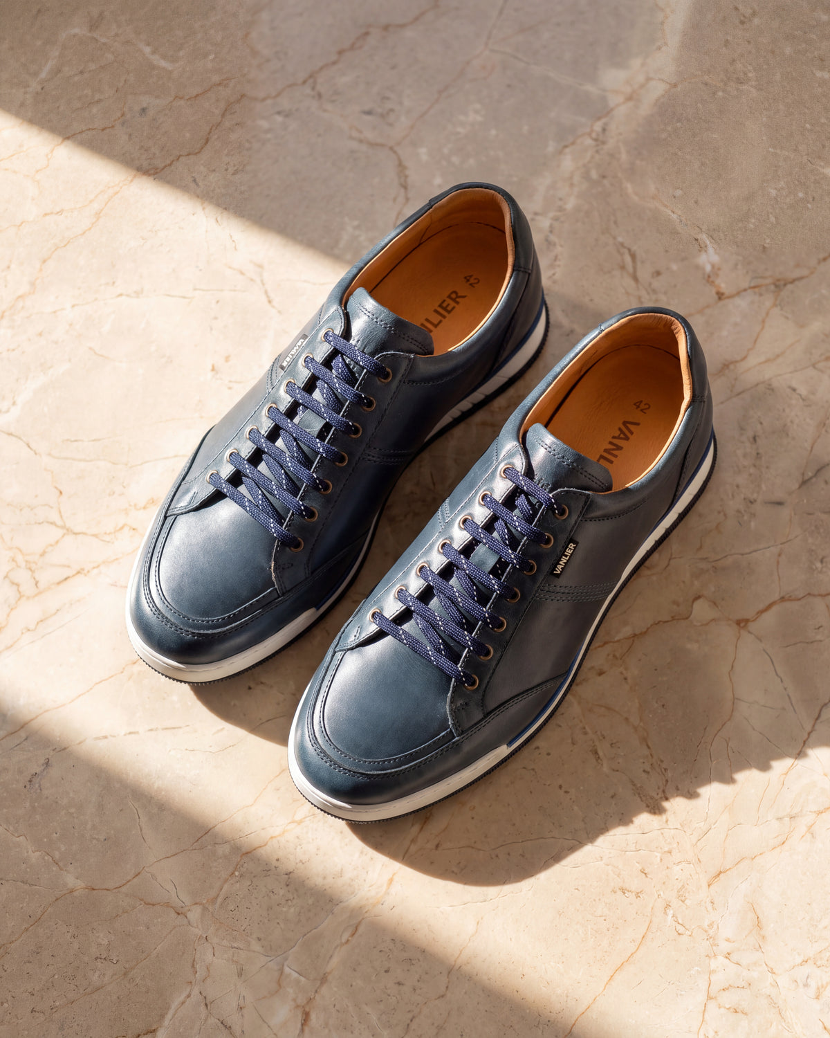 Blauw gladleren Magnus sneaker – detail van het paar op marmer