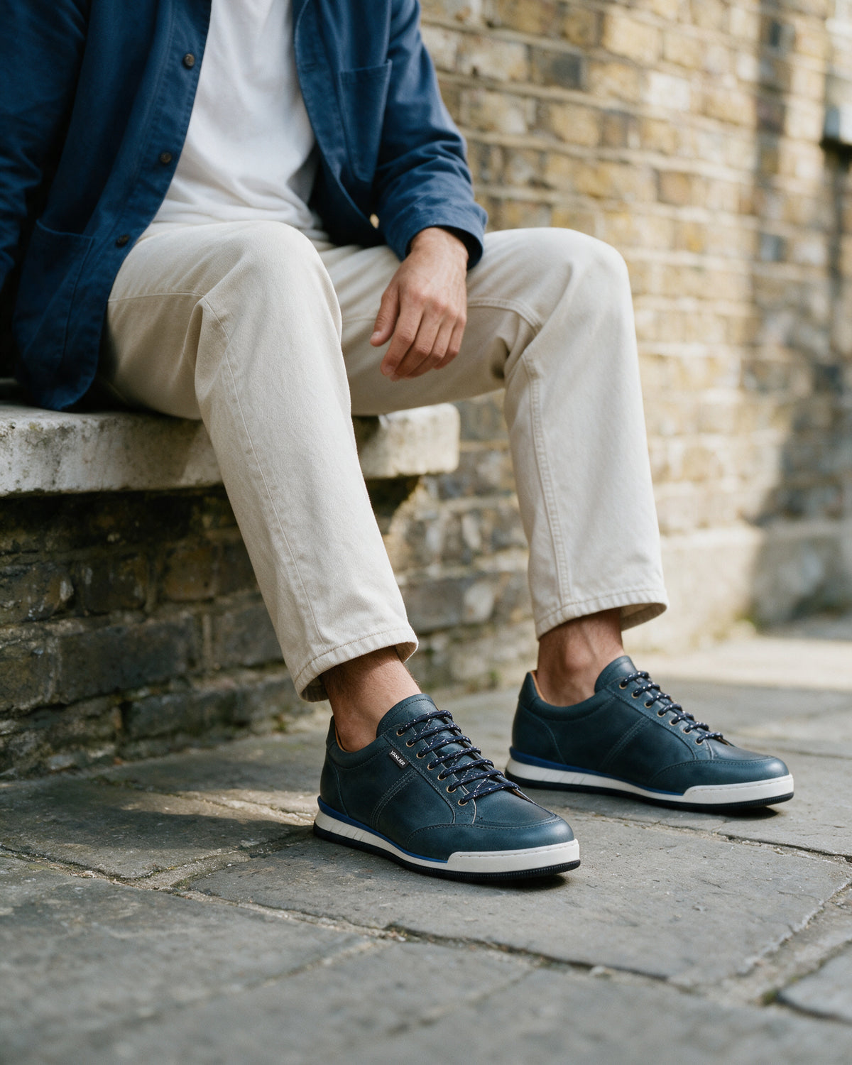 Blauw gladleren Magnus sneaker – gedragen, zittend op een trap