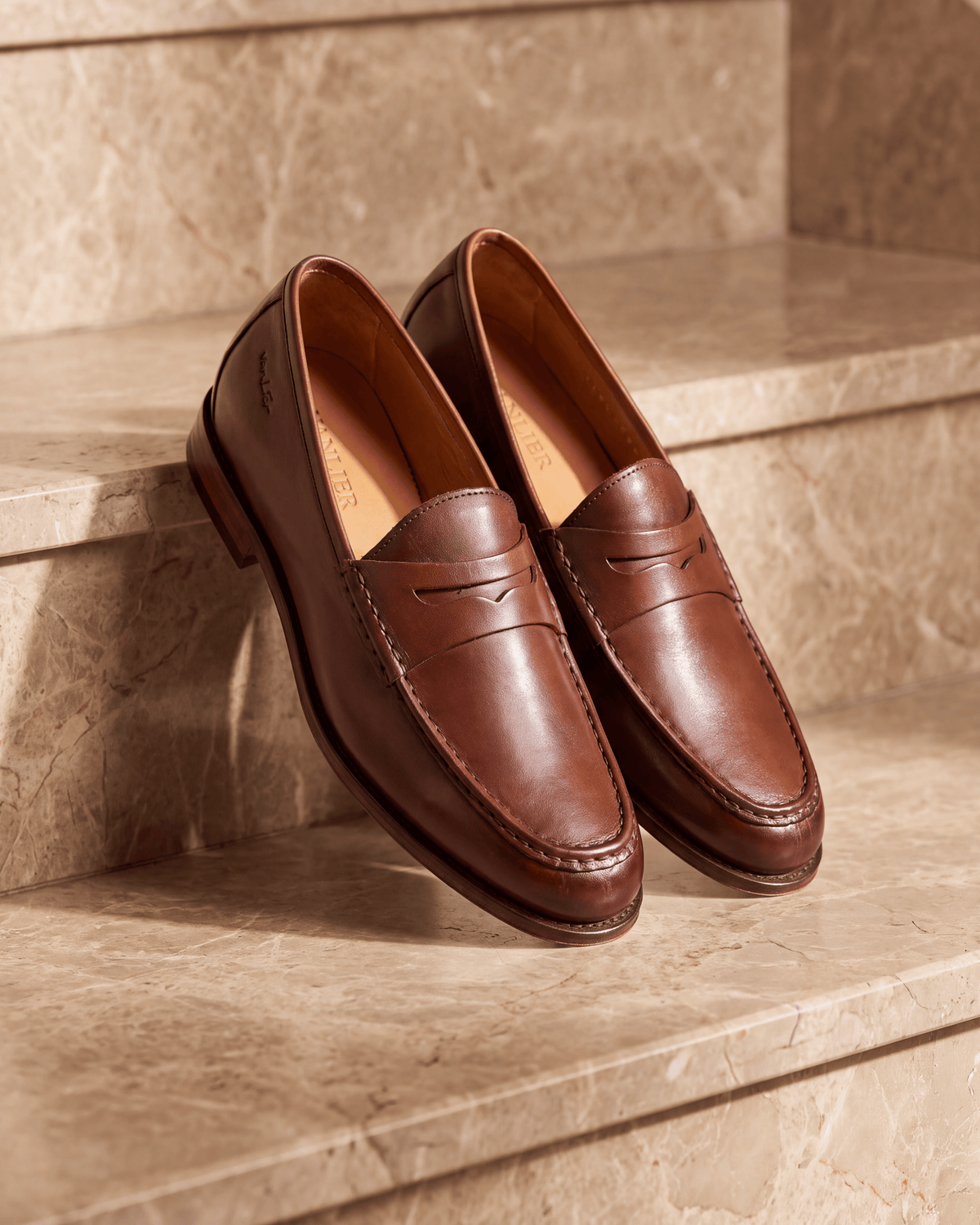 Cognac gladleren Cambridge Penny loafer – stilleven op warm marmer