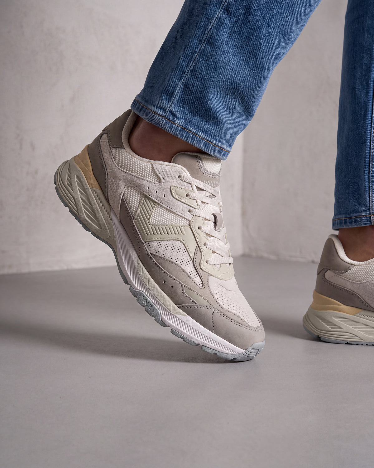 Wit lichtgroen combi Cosmos sneaker – close-up van het paar in een betonnen atelier