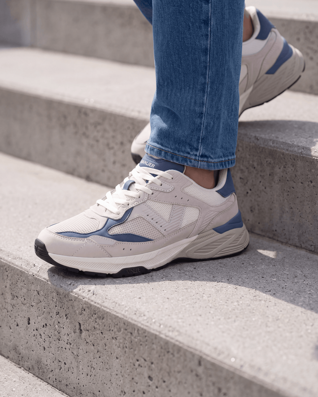 Wit lichtblauw combi Cosmos sneaker – gedragen op een betonnen trap