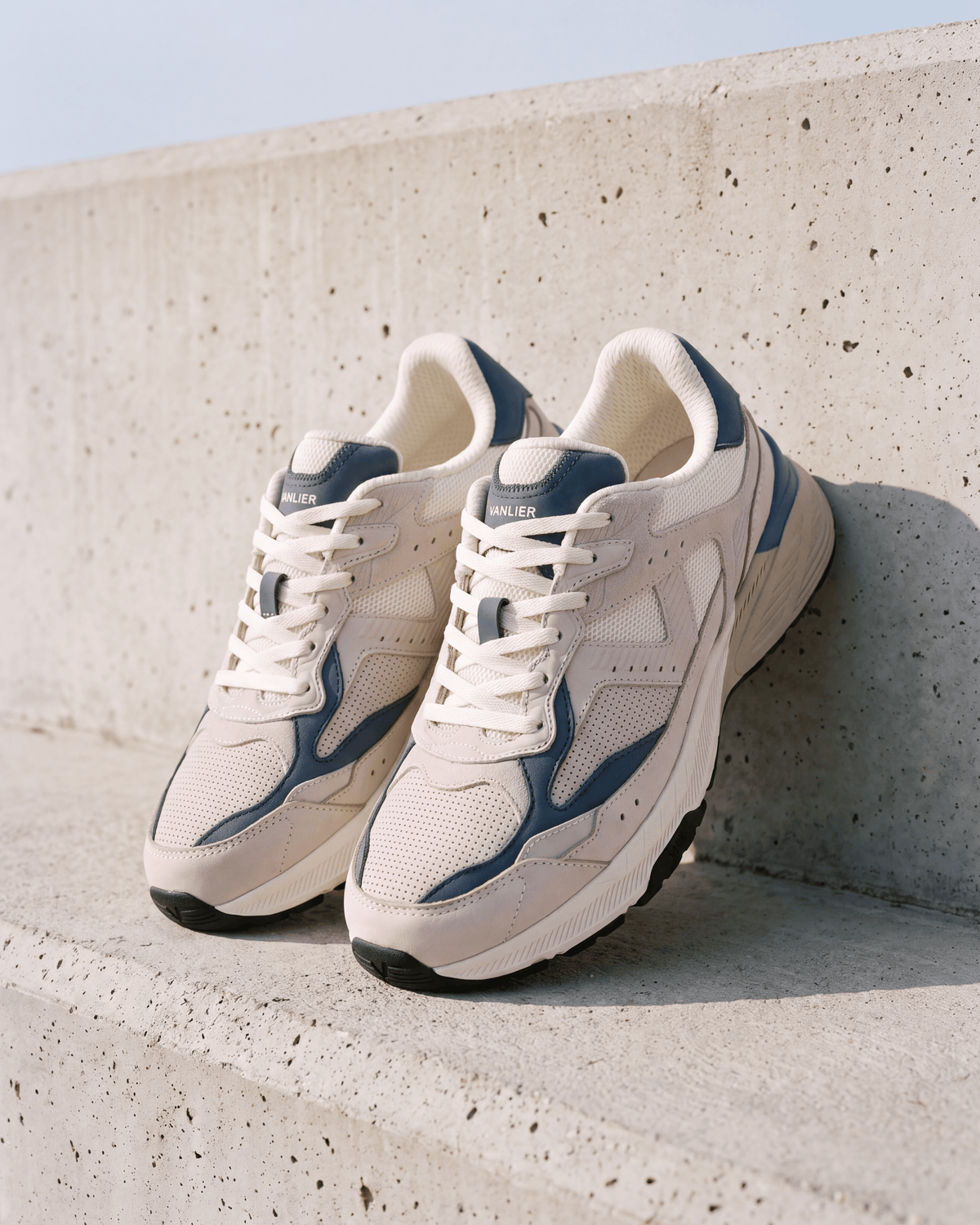 Wit lichtblauw combi Cosmos sneaker – paar leunend tegen een betonnen muur