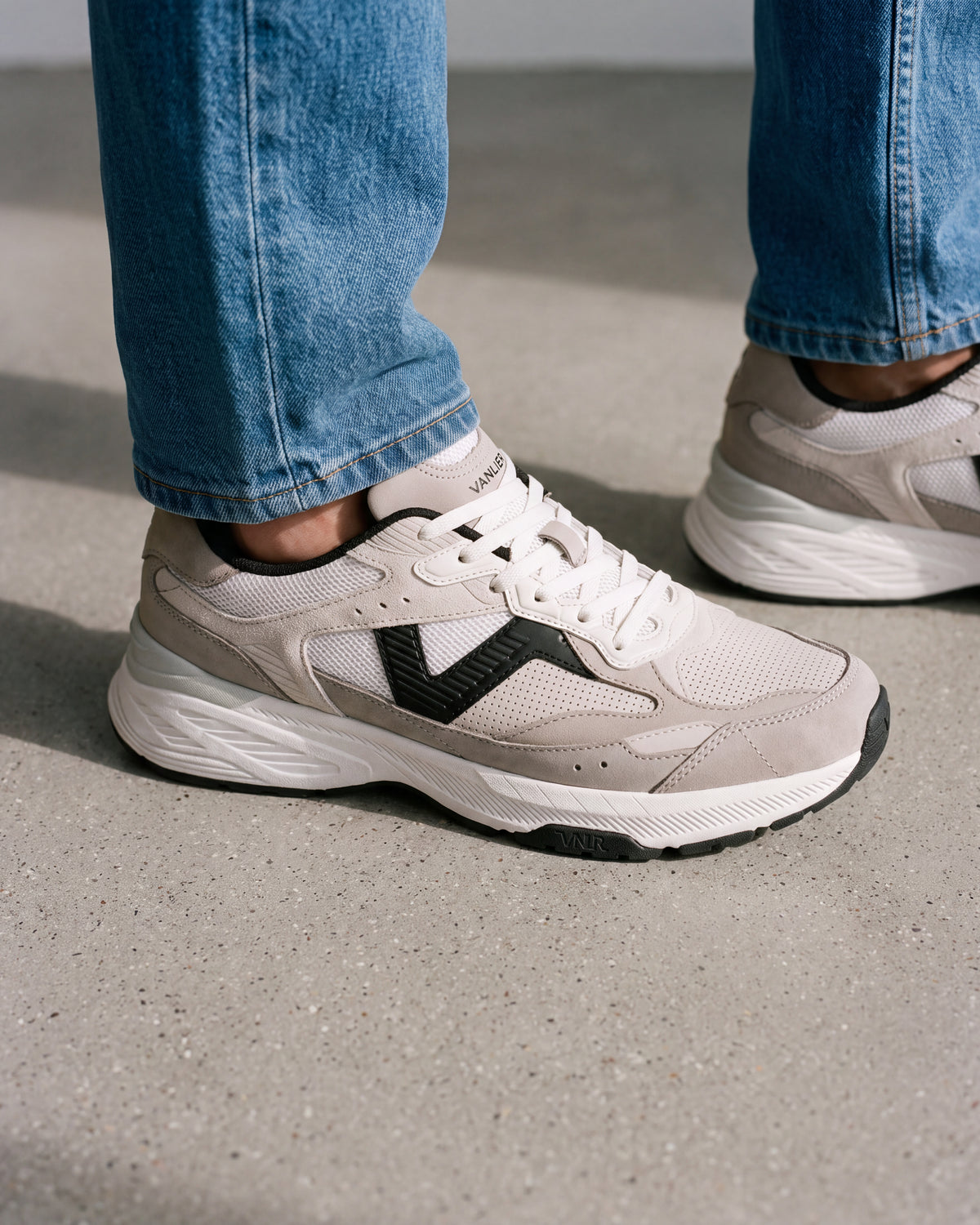 Wit zwart combi Cosmos sneaker – close-up van het paar op een ruwe betonnen vloer